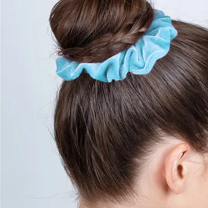 Light blue velvet scrunchie shown on a hair bun with soft fabric texture and elegant shine