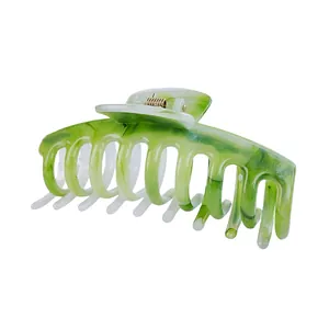 Dettaglio molletta per capelli verde marmorizzato con molla dorata su fondo bianco