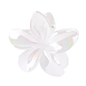 Detailed macro of iridescent white frangipani flower hair claw with a pearly finish