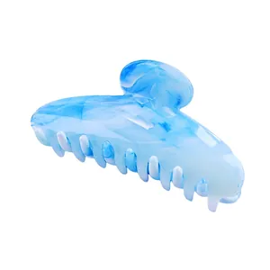 Macro view of large hair claw clip with blue and white marble pattern in acetate finish