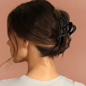 Minimalist black heart claw clip for women's bun hairstyles on brown hair background