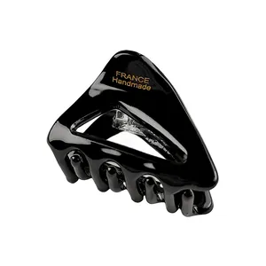 Close-up of a glossy black acetate triangle hair claw clip with gold France handmade logo