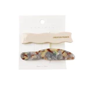 Detail of beige wavy and grey marble acetate hair clips on a white display card