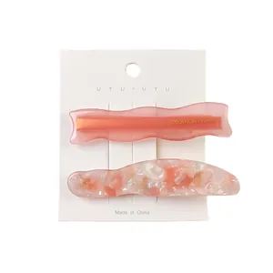 Pink acetate marble hair clip set on display card with wave edges and gold text detail
