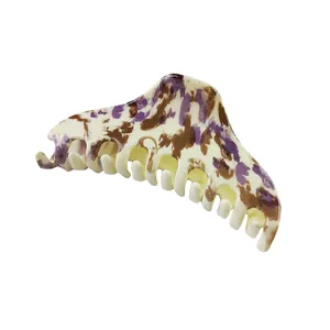 Detailed view of cream hair claw clip with purple and brown artistic ink splashes