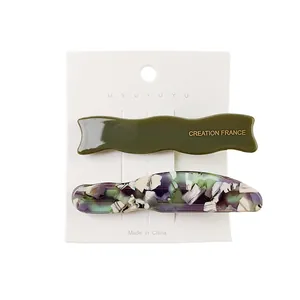 Detail of olive green wavy hair clip and marble texture hairpin on display card