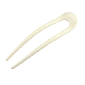 Detail view of a cream-colored U-shaped resin hair fork with a smooth polished finish