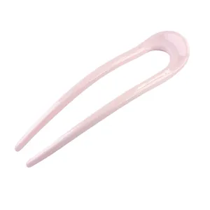Close-up of a minimalist smooth pink U-shaped hair pin with a glossy ceramic-like finish