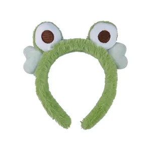 Detail of plush green frog headband featuring soft faux fur and large cartoon eyes