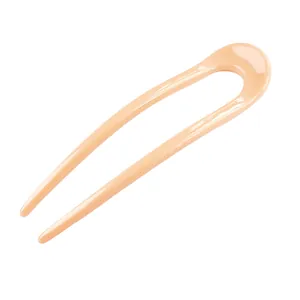 Close-up of minimalist U-shaped hair pin in glossy peach orange finish for sleek styling