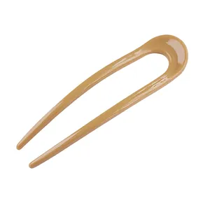 Detail of a glossy amber U-shaped hair pin for buns with a smooth resin finish