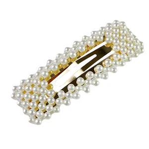 Dettaglio di un fermaglio dorato per capelli con perle finte bianche intrecciate a mano