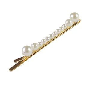 Dettaglio del fermaglio per capelli dorato con perle bianche fatte a mano e sfumate