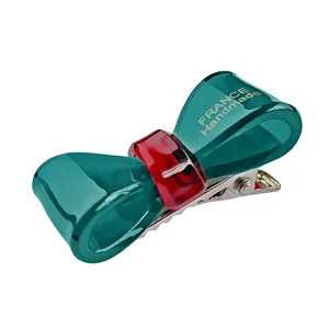 Vue détaillée d'une barrette nœud faite main en acétate vert et rouge avec pince métal