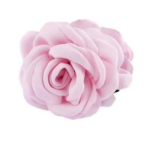 Détail d'une pince à cheveux rose en tissu avec des pétales de mousseline superposés