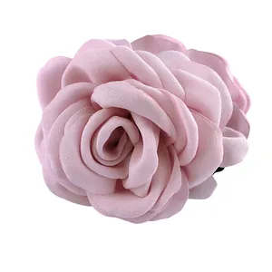 Détail d'une pince à cheveux rose en forme de rose avec des pétales en tissu multicouche