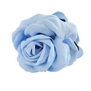 Détail de la rose en tissu bleu clair avec pétales superposés sur une pince à cheveux