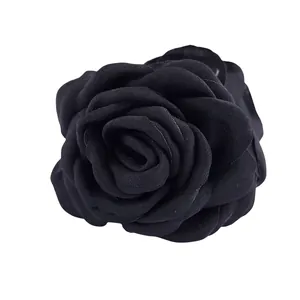 Vue détaillée d'une pince à cheveux rose en tissu noir multicouche avec des pétales texturés