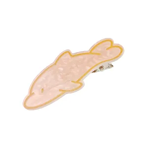 Détail de la pince à cheveux dauphin rose avec texture nacrée et accents jaunes