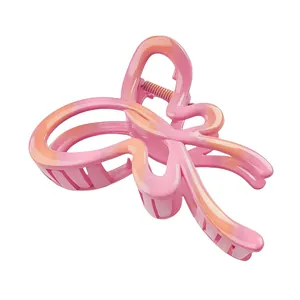 Macro view of gradient pink and orange butterfly hair claw with hollow design detail
