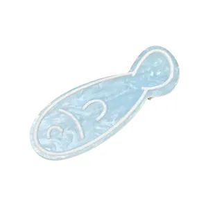 Détail de la pince à cheveux poisson bleu clair avec texture marbrée nacrée et motifs