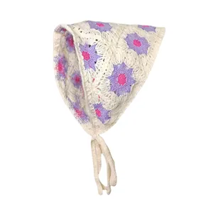 Detail van gehaakte driehoekige bandana met paarse madeliefjes en bandjes op witte achtergrond