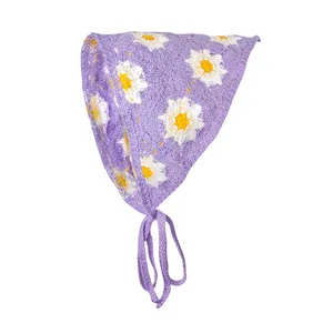 Detail van gehaakte textuur van paarse bandana met witte madeliefjes en strikbanden