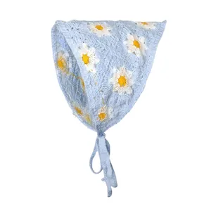 Detail van lichtblauwe gebreide baby muts met witte madeliefjes en handige strikbandjes
