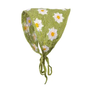 Detailopname van grasgroene gehaakte bandana met witte madeliefjes bloemmotieven