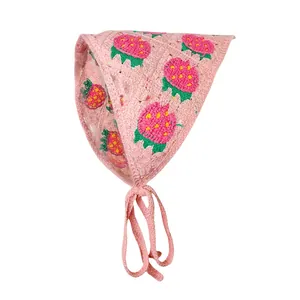 Detail van roze gehaakte hoofddoek met handgemaakte aardbeipatronen en geweven bandjes