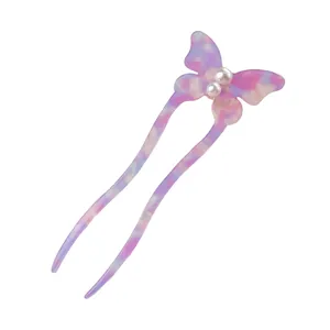 Detail of butterfly hair fork with marble texture, twin prongs, and pearl accents