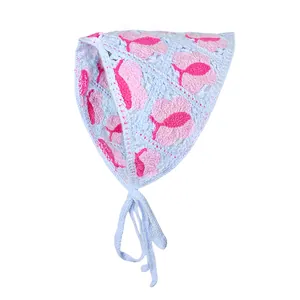 Detail van een lichtblauwe gehaakte bandana met roze bloemen en handige strikbandjes