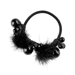 Detailed macro view of black elastic hair tie with soft faux fur pom-poms and glossy beads