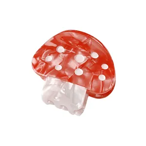 Détail de la pince à cheveux champignon rouge avec pois blancs et texture acétate nacrée