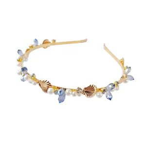 Detail of a gold headband featuring white pearls, blue crystals, and sea shell accents