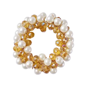 Elastic hair tie with white pearls and amber crystal beads on a white background