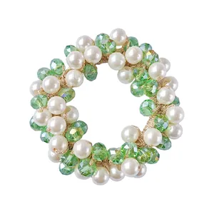 Detailed view of elastic hair tie with white faux pearls and green faceted crystal beads