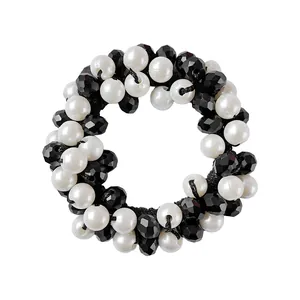 Detail of beaded hair tie with white faux pearls and black faceted beads on elastic band