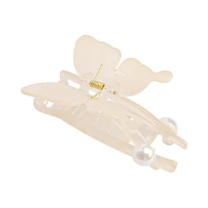 Detail showing creamy translucent butterfly hair claw with gold spring and pearl accents
