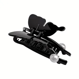 Detail of glossy black butterfly hair claw clip with white pearls and sturdy metal spring