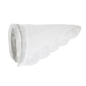 Dettaglio di maniche decorative in pizzo bianco con ricami floreali e piccoli pompon
