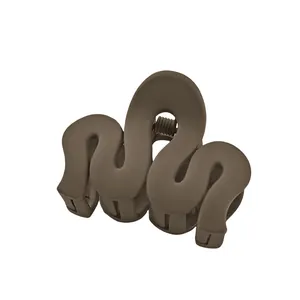 Detail of matte brown hair claw clip with wavy curve design and metal spring mechanism