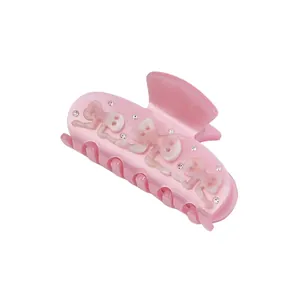 Close-up of pink acetic hair claw clip featuring rhinestones and white letter details