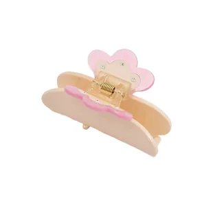 Detail view of pink and beige acetate hair claw with floral petals and sparkling rhinestones