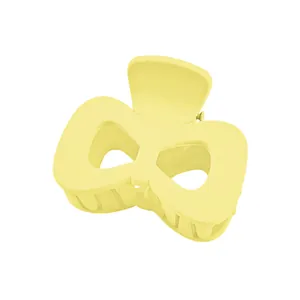 Detail of light yellow matte bow hair claw clip with hollow wings and sturdy inner teeth