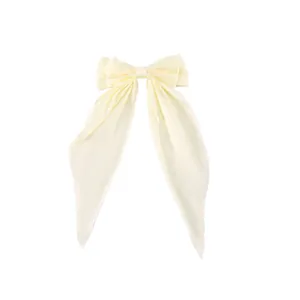 Detail of a cream-colored fabric bow hair clip with long elegant hanging ribbons