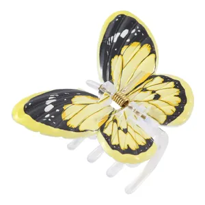 Détail de la pince à cheveux papillon avec des ailes à motifs jaune et noir et ressort doré