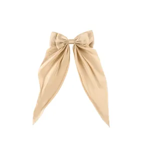 Close-up of champagne satin bow hair clip with elegant long ribbon detail and silky texture