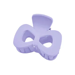 Macro detail of a matte light purple bow hair claw clip with crossed teeth design
