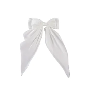 Detail of white satin double-layered bow hair clip with elegant long trailing ribbons